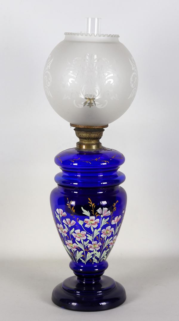 Antico lume a petrolio a forma di anfora in vetro blu cobalto, con decorazioni di fiori in smalti a rilievo, globo in vetro inciso. Trasformazione a luce elettrica