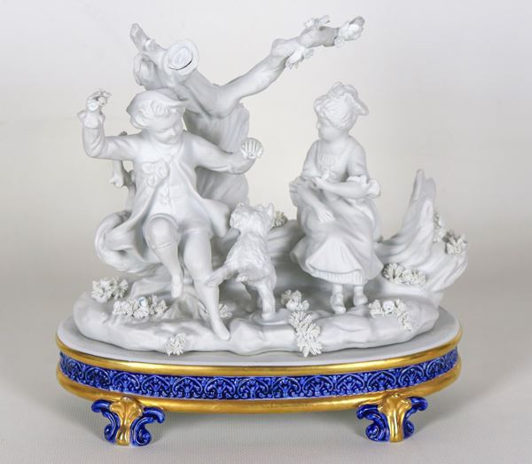 "Allegoria di bambini con cagnolino", gruppo in biscuit bianco di Capodimonte, con base ovale in blu e oro zecchino sorretta da quattro piedini