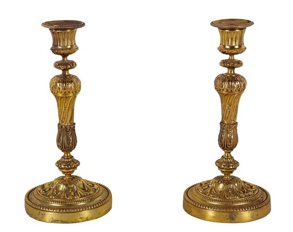 Pair of antique French candlesticks in gilded bronze, chiseled and embossed, with the bronzesmith's stamp on the base. First Half of the 19th Century