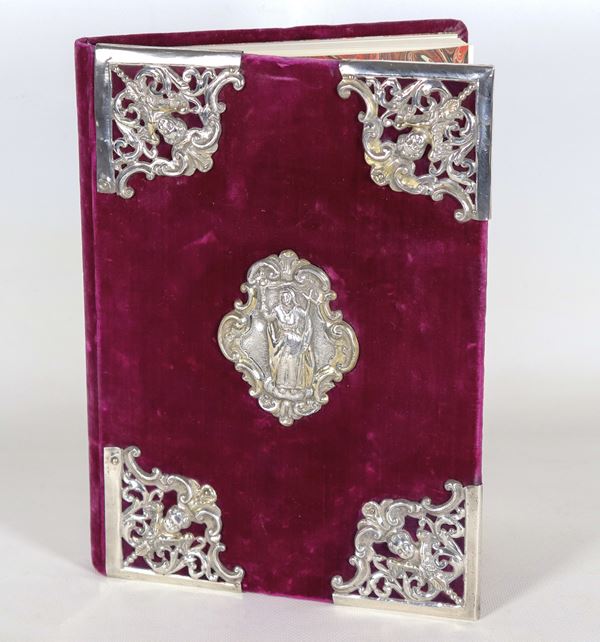 Commemorative book for signatures, with purple red velvet covering and applications of ancient friezes in chiseled and embossed silver, with angel heads at the corners and the figure of Santa in the center