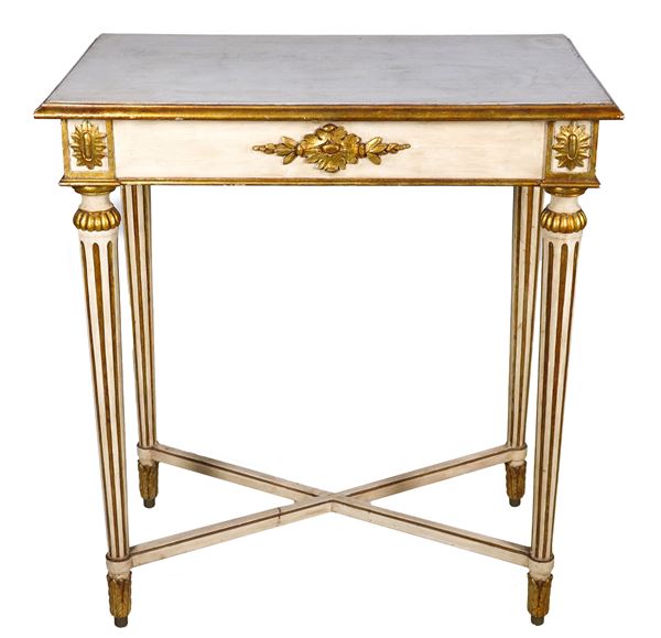 French center table of the Impero line, in ivory lacquered wood with gilded and carved neoclassical friezes, four cone-shaped legs joined by a cross