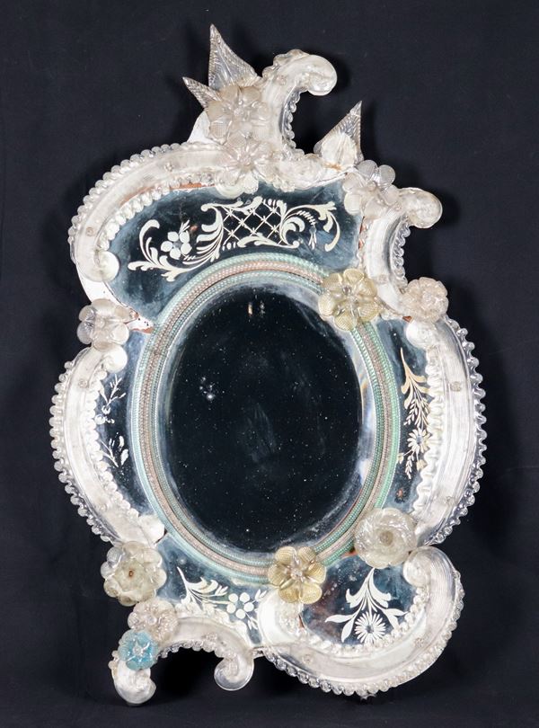 Antica piccola specchiera ovale in vetro soffiato di Murano, con applicazioni di fiori e vetri del bordo incisi. Lievi mancanze