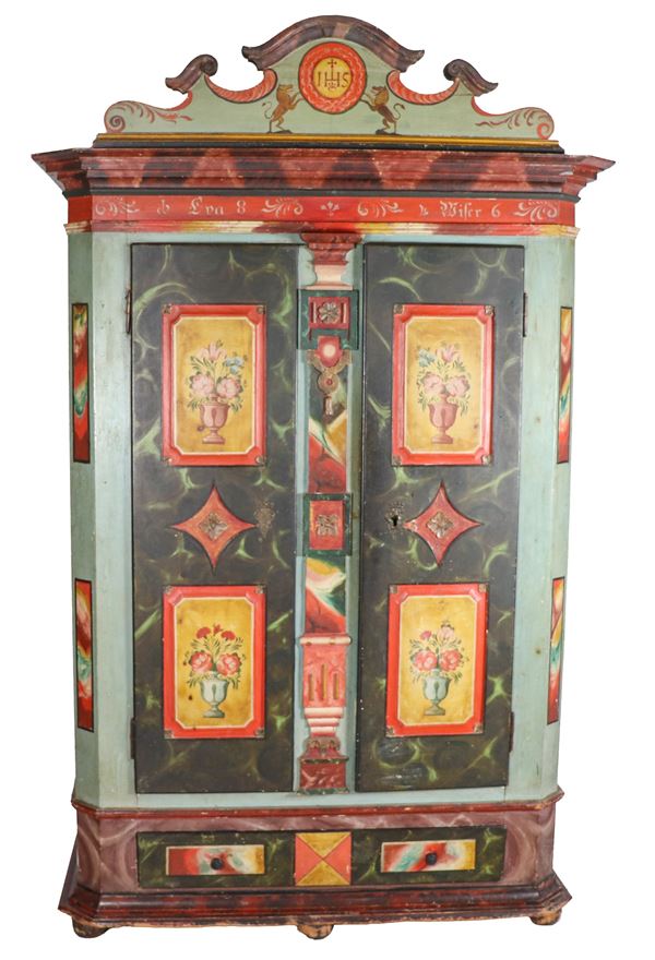 Antique Tyrolean wardrobe with two doors and drawer underneath, in lacquered wood and decorated with imitation marble, with pilaster strips and panels painted with geometric motifs and vases with flowers, shaped cymatium and onion legs with traces of woodworms. Second half of the 19th century