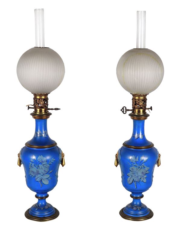 Coppia di antiche lampade a petrolio francesi in vetro laccato blu con decorazioni a motivi floreali, cannule e globi in vetro soffiato. Un globo presenta rottura