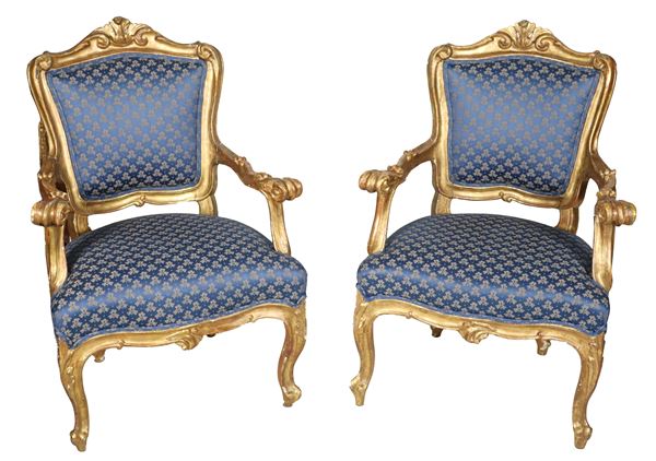 Coppia di antiche poltrone romane di linea Luigi XV, in legno dorato e intagliato con braccioli e manici ricurvi, copertura in tessuto blu fiorato