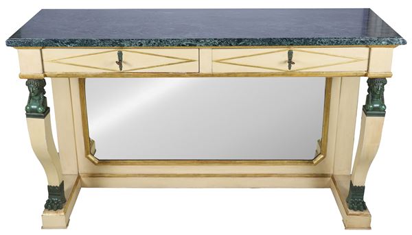 Empire line console in ivory lacquered wood with golden profiles, two drawers and two curved legs with small bronze sculptures of Egyptian heads and lion feet resting on a shaped base with central mirror, top in green Alpine marble