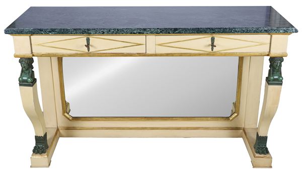 Consolle di linea Impero in legno laccato avorio con profili dorati, due tiretti e due gambe ricurve con piccole sculture in bronzo di teste egizie e piedi leonini poggianti su base sagomata con specchio centrale, piano in marmo verde delle Alpi
