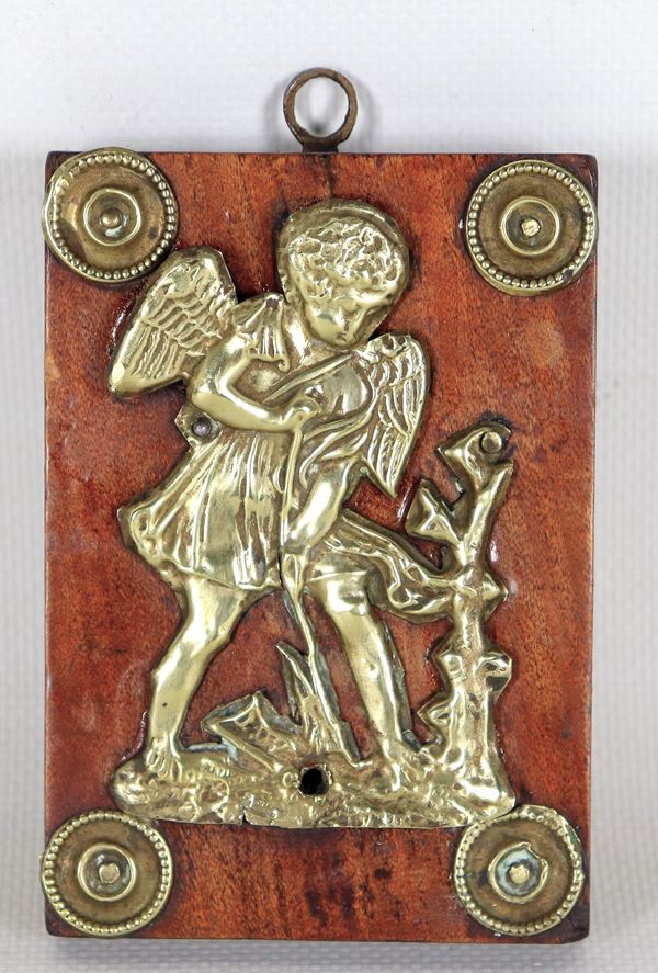 "Cupid plowing the field", ancient small Roman bas-relief in gilded copper, embossed and chiselled, mounted on a walnut tablet with rosettes