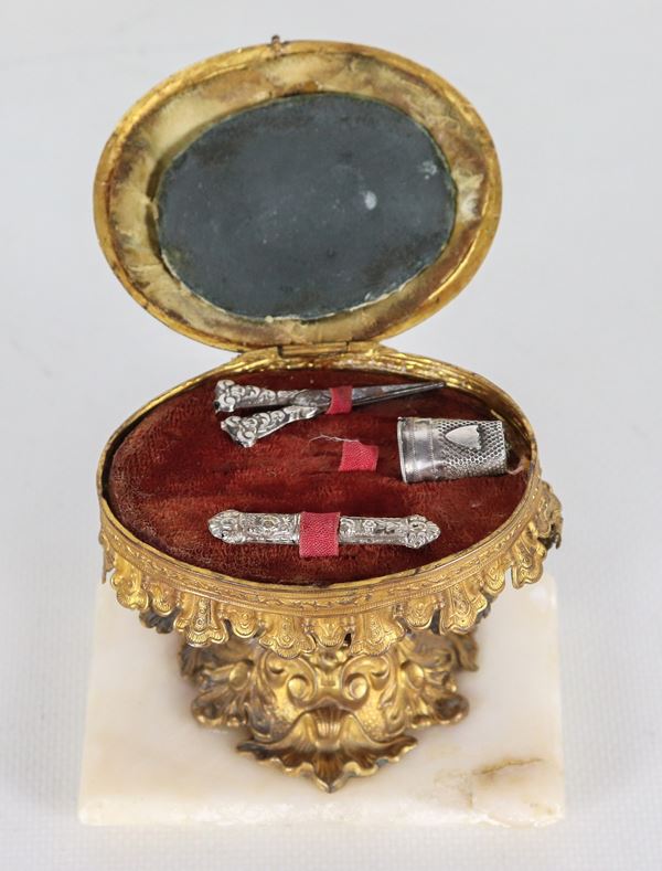 Antico modellino di tavolinetto da lavoro romano in argento e metallo dorato, sbalzato e cesellato, con piccola miniatura ovale dipinta sul coperchio ribaltabile. All'interno due piccoli utensili per cucito, basetta in marmo bianco