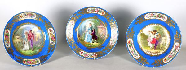 Lot of three antique wall plates in light blue Sèvres porcelain, with colorful medallions of gallant scenes, pure gold edges and bunches of flowers. Two plates are damaged