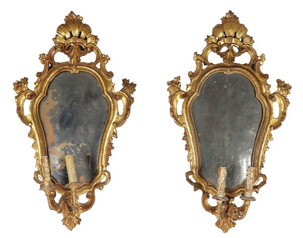 Coppia di specchiere a ventolina, in legno dorato e intagliato a motivi Luigi XV di ricci, fiori e conchiglie, specchi al mercurio, due luci ciascuna difettate