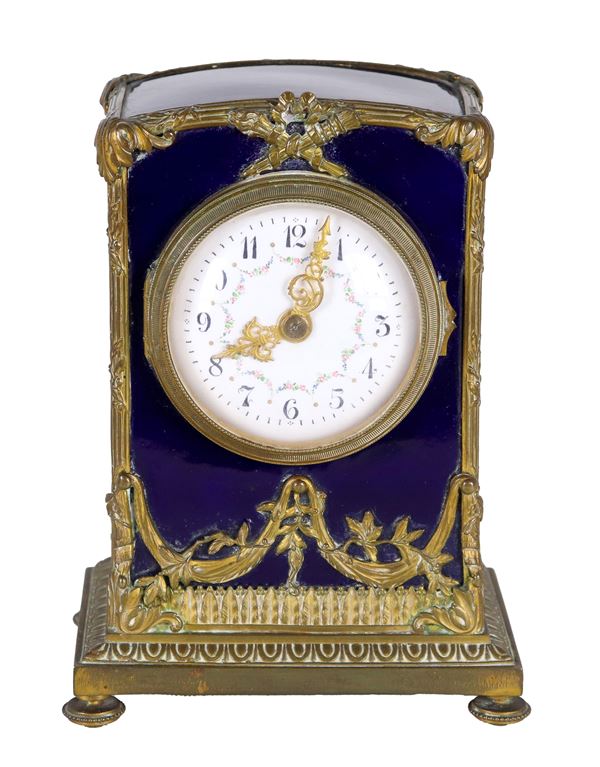 Antique small French table clock in ceramic covered in blue enamel, with gilded and chiseled bronze trimmings and friezes, white enamel dial decorated with floral garlands