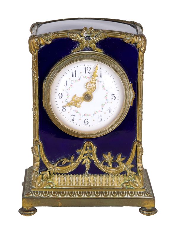 Antica piccola pendola da tavolo francese in ceramica rivestita in smalto blu, con guarnizioni e fregi in bronzo dorato e cesellato, quadrante in smalto bianco decorato a ghirlande floreali