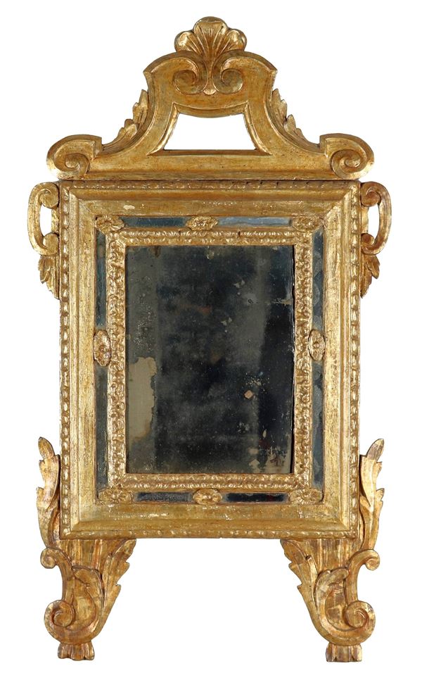 Antica piccola specchiera marchigiana, in legno dorato e intagliato a motivi Luigi XV di ricci, cordoni  e motivi vegetali, cimasa sagomata e specchio al mercurio