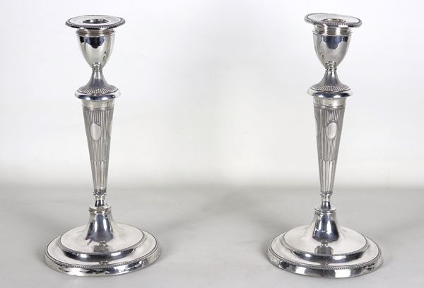 Coppia di antichi candelieri Giorgio III, in argento cesellato e sbalzato a motivi di baccellature e perlinature, lievi ammaccature ai bordi delle basi, gr. 820. Bolli Sheffield 1787