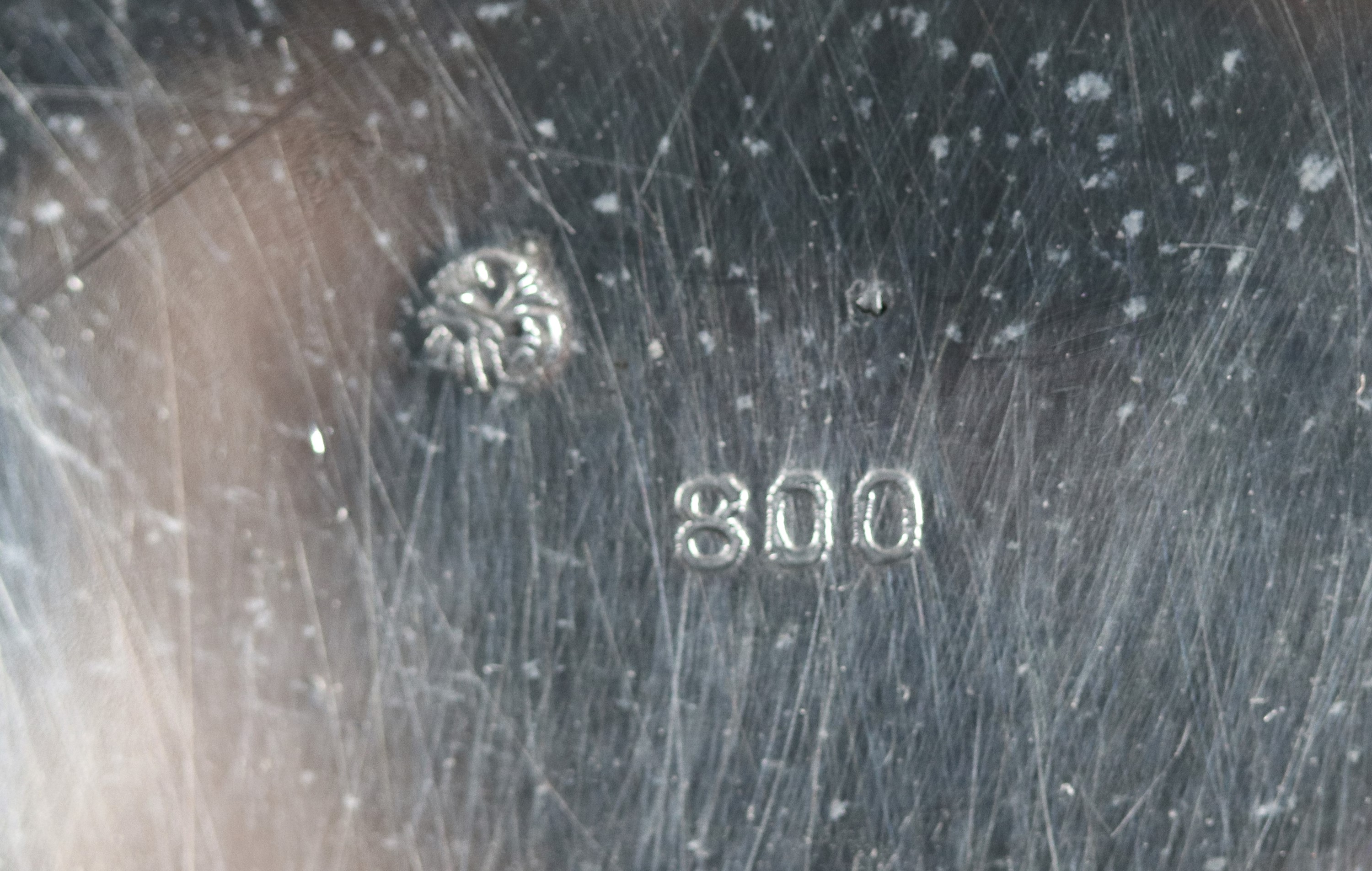 Antico centrotavola tondo in argento con bordo smerlato e baccellato, sorretto da quattro piedini...