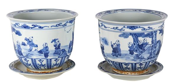 Pair of Chinese cachepots with saucers, in white porcelain with blue decorations depicting oriental life scenes