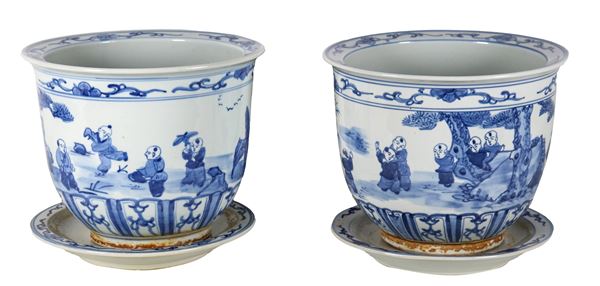 Coppia di cachepots cinesi con sottovasi, in porcellana bianca con decorazioni in blu a scene di vita orientale