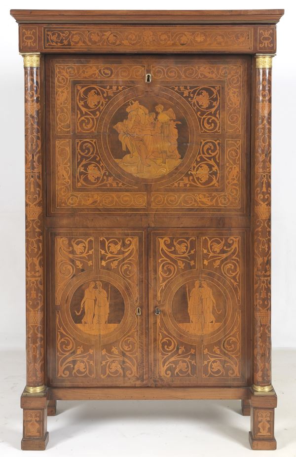 Antico secretaire lombardo in noce, Epoca Primo Impero, interamente intarsiato a motivi neoclassici con volute di foglie d'acanto, filettature e medaglioni con scene mitologiche. Calatoia formante scrittoio con tiretti e scomparto centrale, un tiretto sovrastante, due sportelli sottostanti e due montanti a colonnine neoclassiche con capitelli in bronzo dorato e cesellato