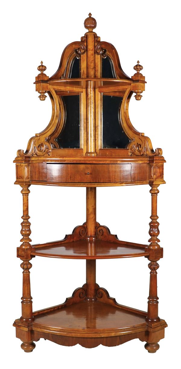 Antica angoliera Luigi Filippo in noce intagliata, con alzata sul piano a forma sagomata con specchi, un tiretto centrale, tre piani e montanti a colonnine tornite e scannellate, gambe a cipolla