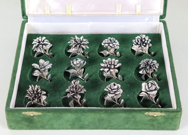 Lot of twelve placeholders in chiselled and embossed silver in the shape of flowers, green velvet case, gr. 250