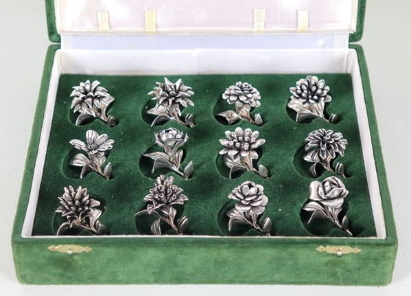 Lotto di dodici segnaposto in argento cesellato e sbalzato a forma di fiori, astuccio in velluto verde, gr. 250 