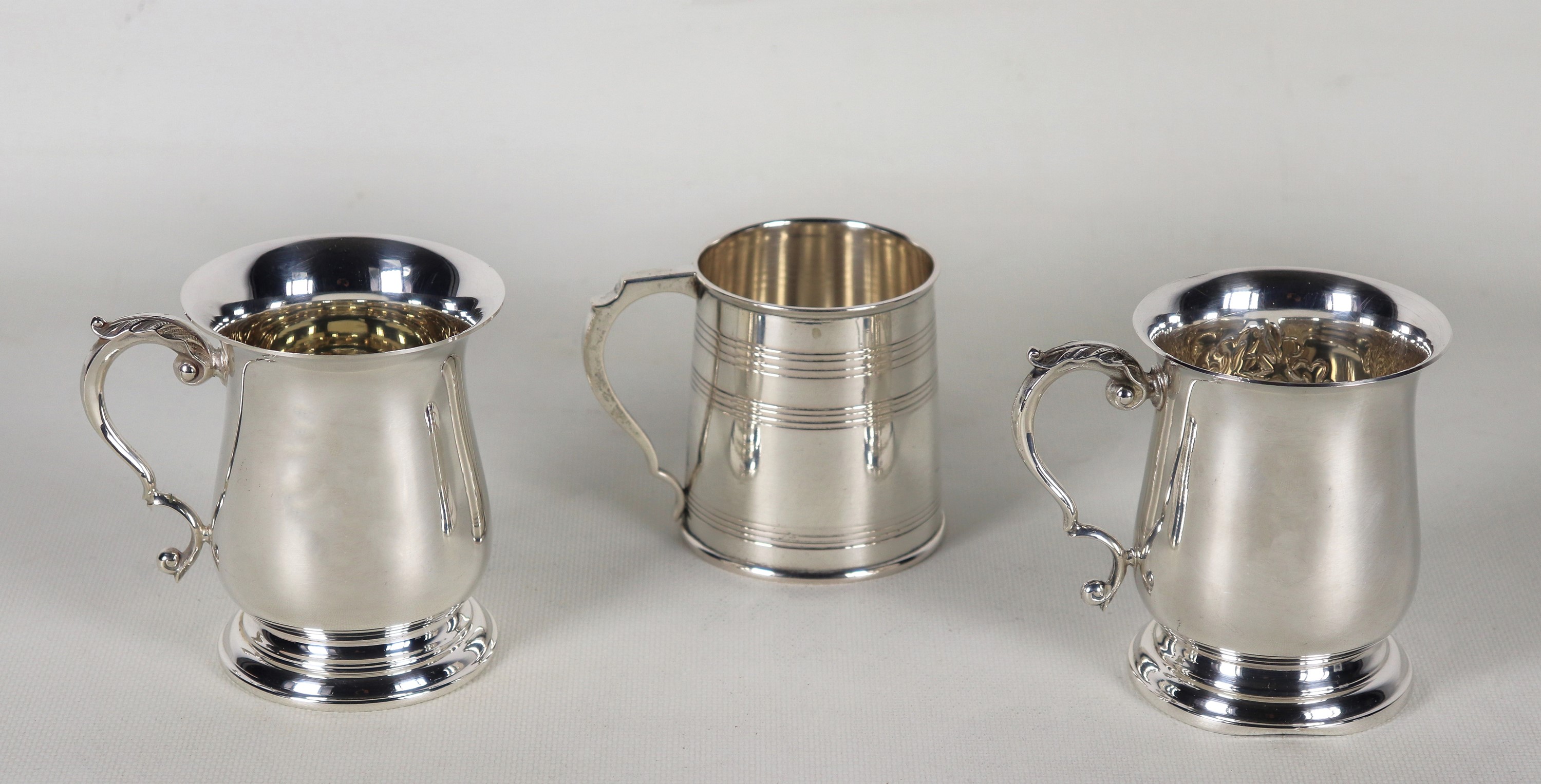 Lotto di tre piccoli boccali in argento cesellato e sbalzato, forme e misure differenti, gr. 555