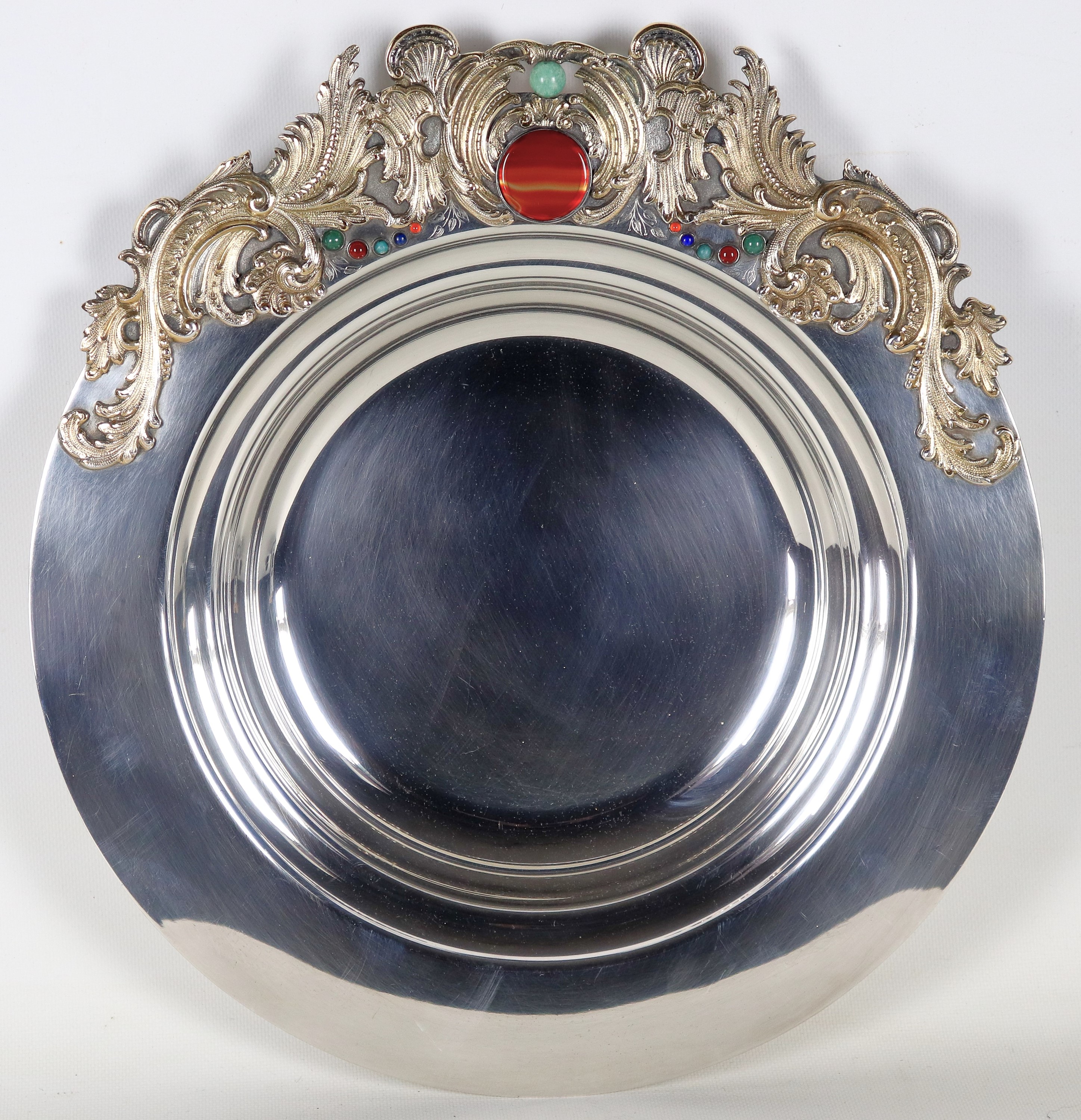 Grande centrotavola in argento, con applicazioni sul bordo di volute dorate e pietre dure. Marcat...