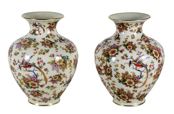 Pair of white porcelain vases with polychrome decorations of bunches of flowers and parrots. The edge of a vase has a small flaw