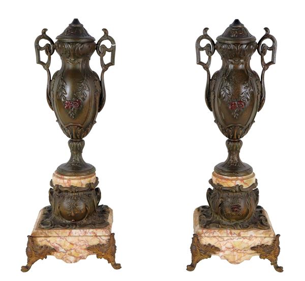 Pair of ancient French amphorae in embossed bronze with floral motifs and volutes, bases in veined pink marble. An amphora has a defective handle