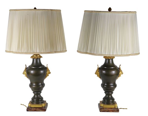 Coppia di anfore francesi in metallo laccato nero, con teste di leoni in bronzo dorato e cesellato e basi quadrangolari. Trasformazione a lumi