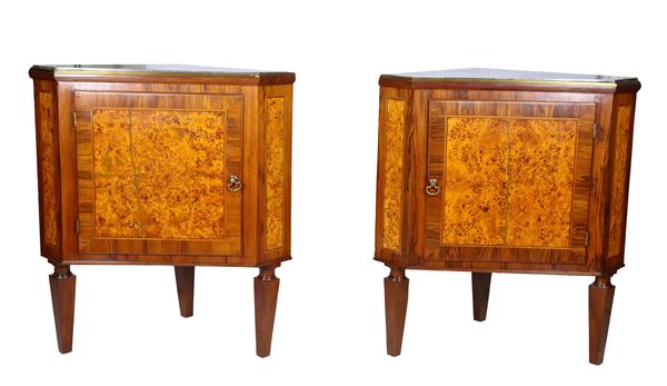 Pair of antique Louis XVI style corner units in purple ebony, thuja root and inlaid threads, shaped with central door, grey veined marble top and three inverted pyramid shaped legs. One marble has a defect