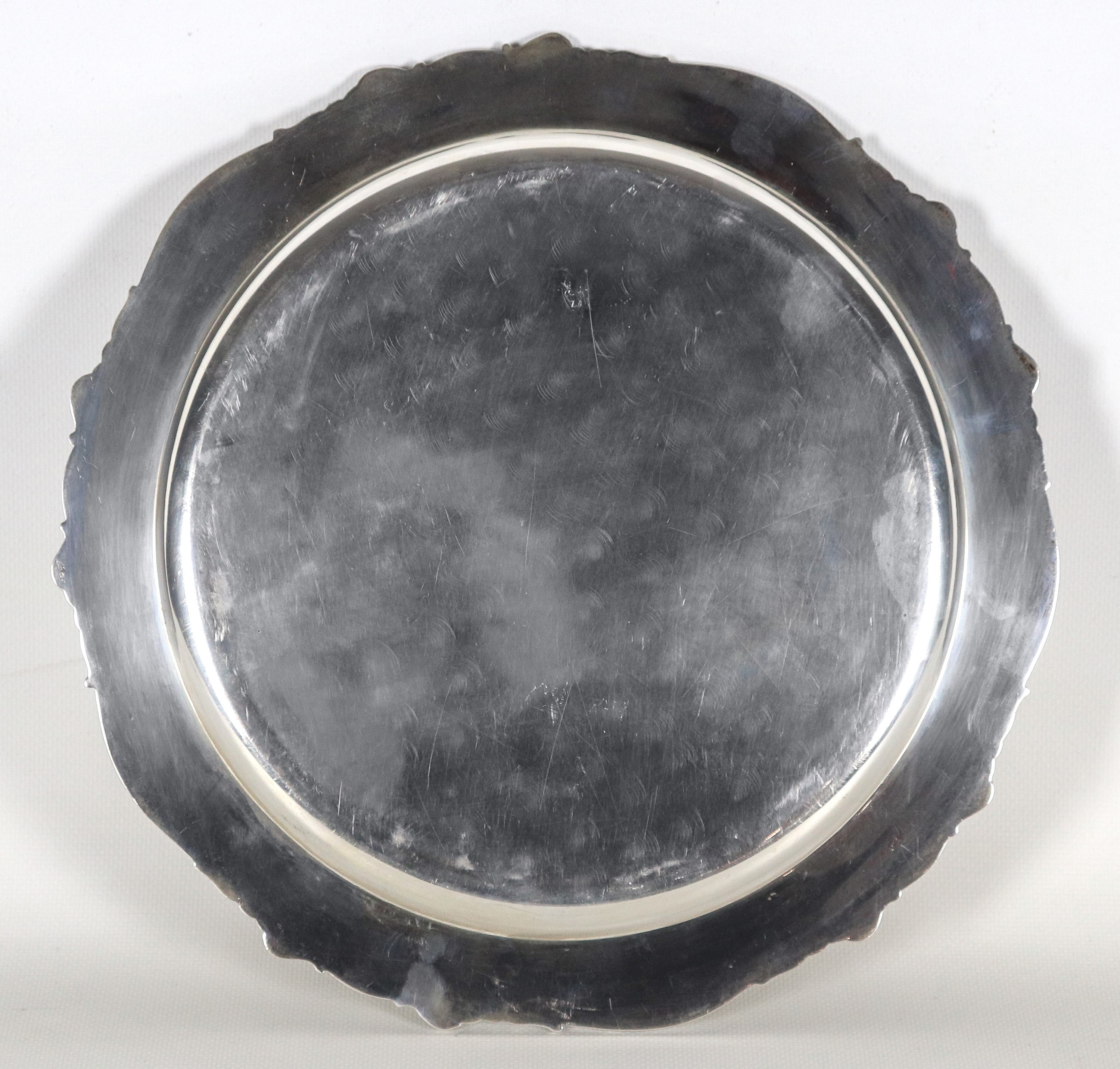 Piatto tondo in argento, con bordo sbalzato e cesellato a volute, gr. 570