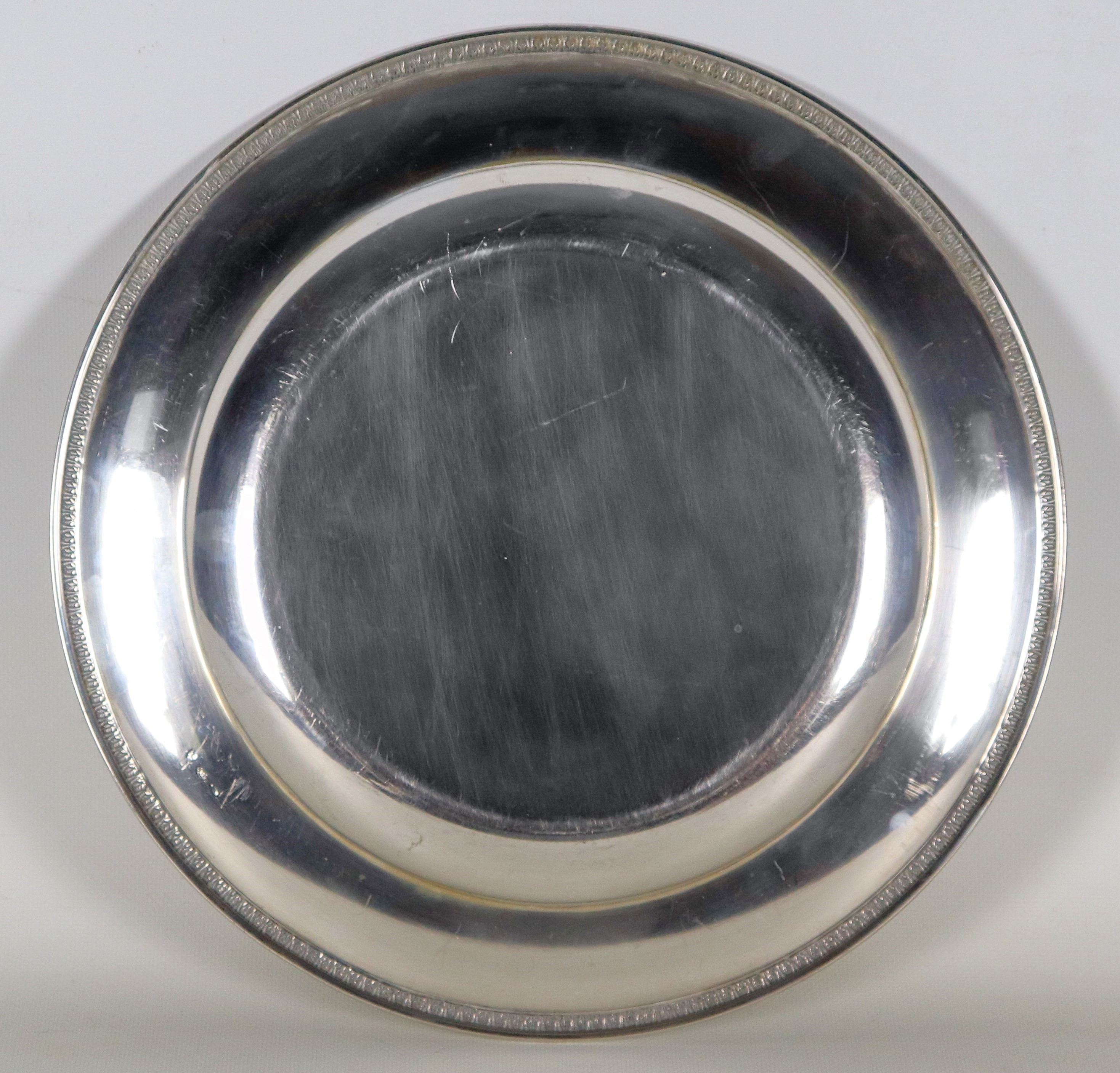 Piatto tondo da portata in argento, con bordo cesellato e sbalzato a motivi Impero, gr. 660