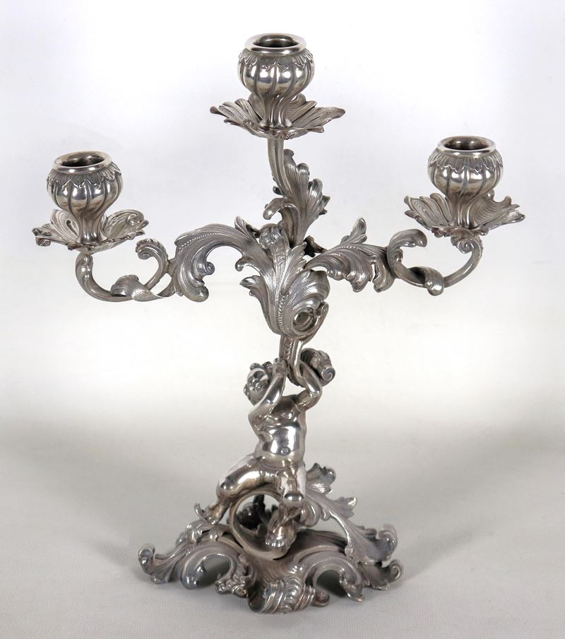 Candelabro in argento cesellato e sbalzato a motivi Luigi XV, sorretto da scultura di putto, 3 fi...