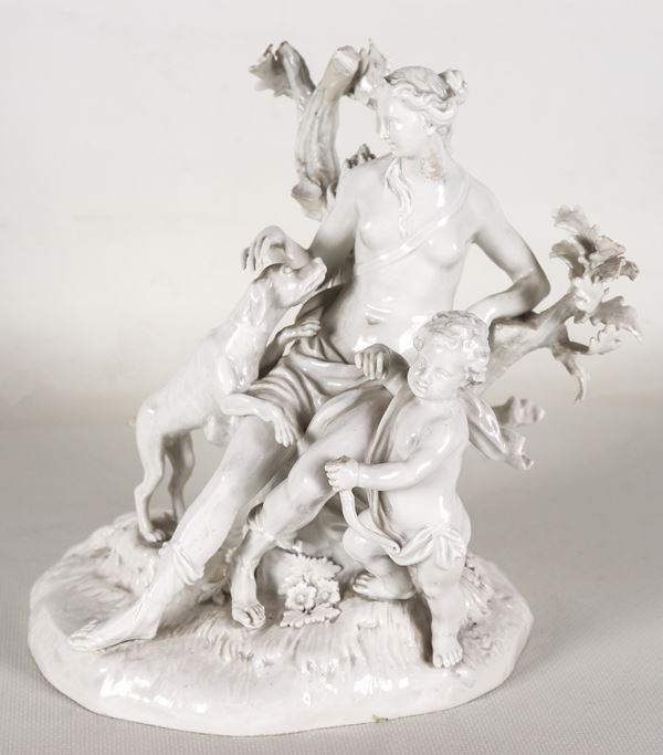"Diana cacciatrice con putto", antico gruppo in porcellana bianca smaltata di Meissen, Secolo XIX. Piccole mancanze all'alberello e alla coda del cane