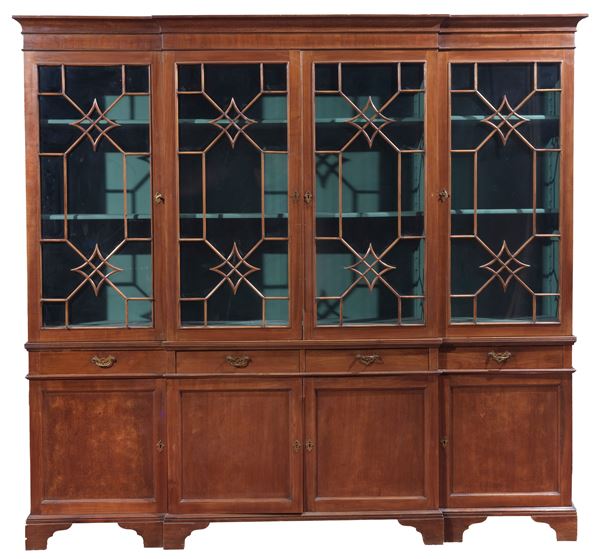 English mahogany bookcase from the Edward VII period, the upper part with four glass doors with shaped feratine, the lower part with four drawers and four paneled doors underneath, catel legs. One upper door has broken glass
