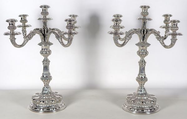 Coppia di candelabri in argento, interamente cesellati e sbalzati a motivi floreali, volute e baccellature, 5 fiamme ciascuno. Bolli Periodo del Fascio, gr. 4290