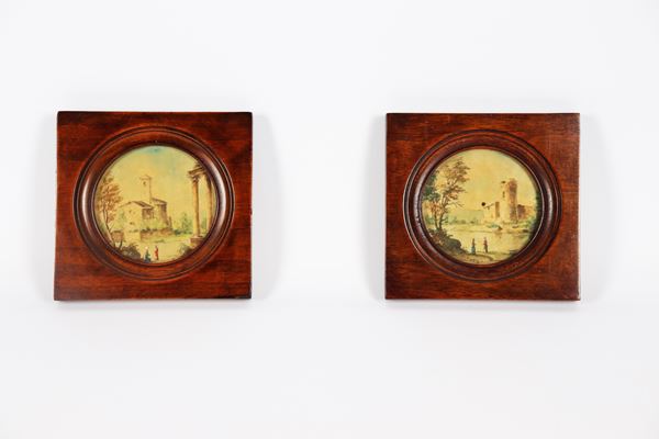 Pair of painted round miniatures depicting &quot;Landscapes with ruins and wayfarers&quot;, walnut frames