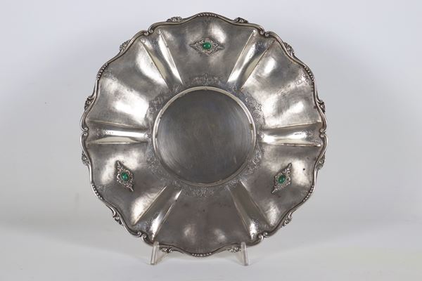 Centrotavola tondo in argento con bordo sagomato e sbalzato e applicazioni di pietre verdi. Manifattura Inizio XX Secolo, gr. 565