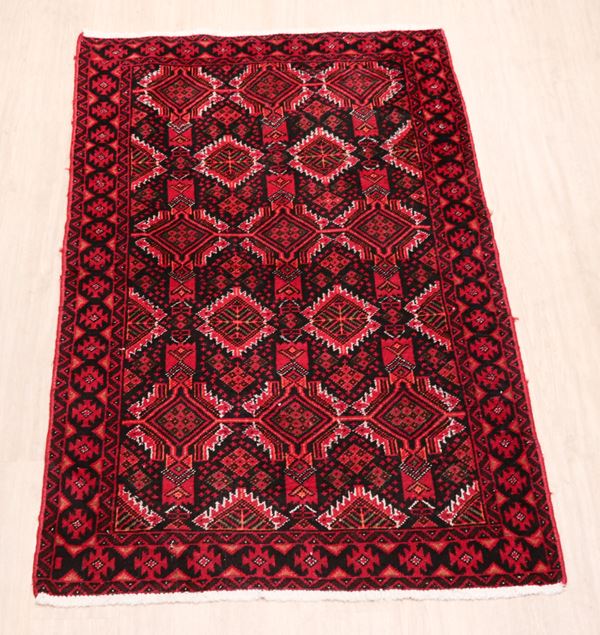 Baluch Persian carpet with geometric patterns on red background