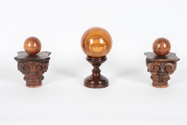 Lot of three decorated wooden spheres. The large one with a turned base, the small ones with capital bases.