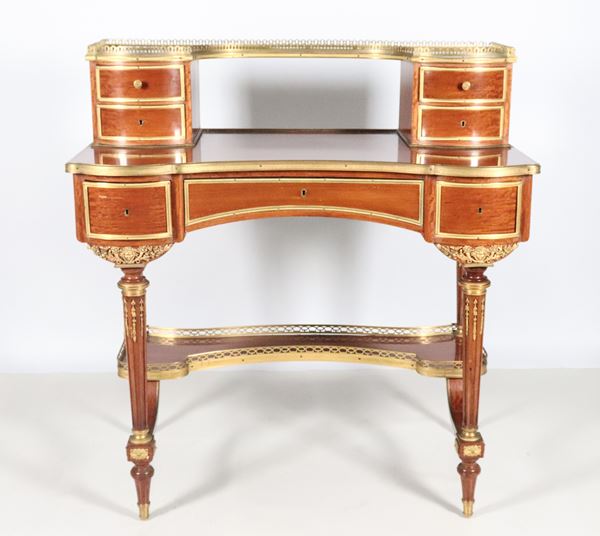 Antique French bonheur du jour of Louis XVI line in mahogany, with gilded bronze fittings and friezes, embossed and chiselled, on the raised top with four drawers, the lower part with three drawers and four fluted conical legs joined by a shaped top with gilded railing