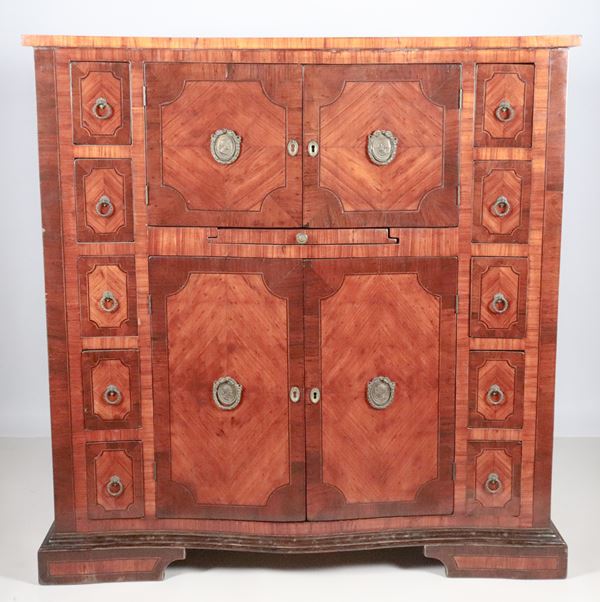 Secretaire francese in bois de rose ed ebano viola, con intarsi a riquadri geometrici e maniglie in bronzo dorato. La parte superiore con due piccoli sportelli con all'interno tiretto scorrevole formante scrittoio, la parte inferiore con due sportelli centrali e cinque tiretti da ambo i lati, piedi a ciabatta