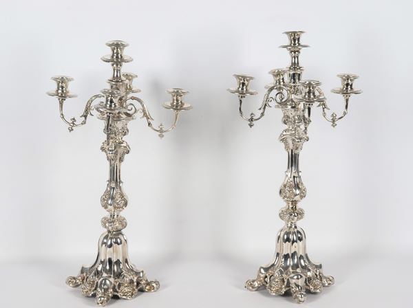 Coppia di antichi candelabri francesi in argento cesellato e sbalzato a motivi di volute, grappoli d'uva e foglie, 5 fiamme ciascuno. Un candelabro presenta alla base difetti e vecchia saldatura, gr. 1360