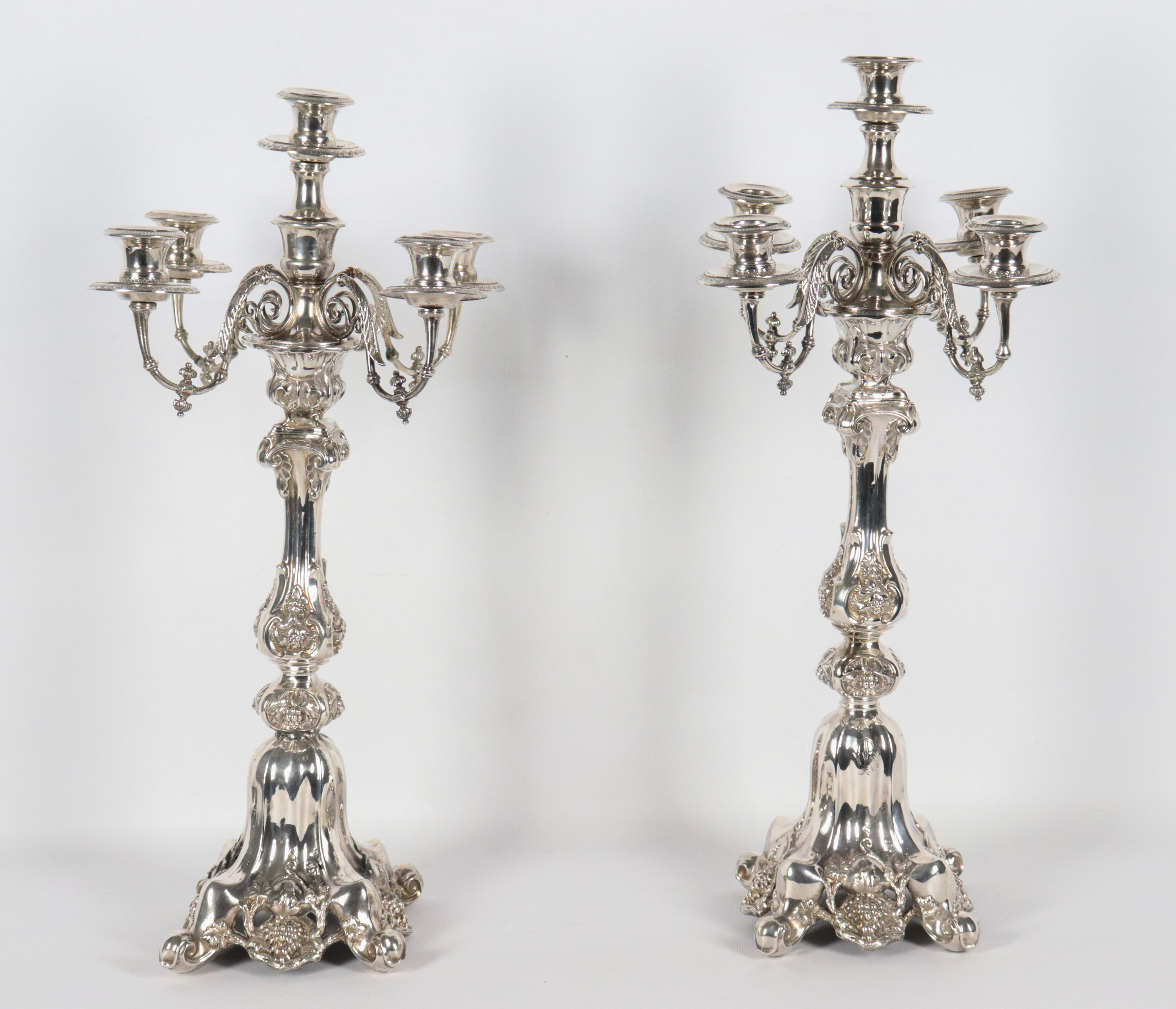 Coppia di antichi candelabri francesi in argento cesellato e sbalzato a motivi di volute, grappol...