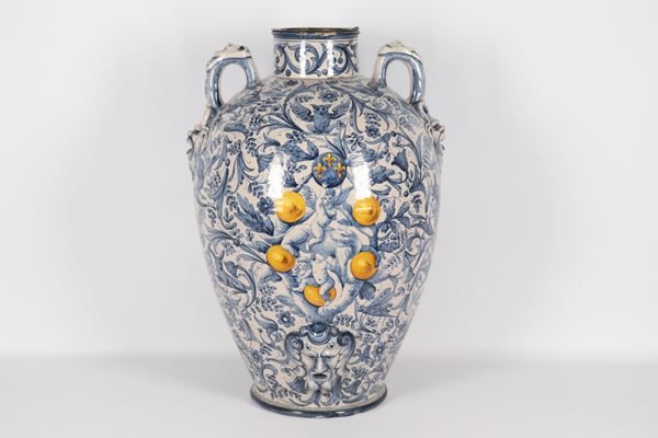 Antico orcio in maiolica italiana, con decorazioni dipinte in blu a volute di fiori e animali, sul davanti e ai due manici mascheroni a rilievo