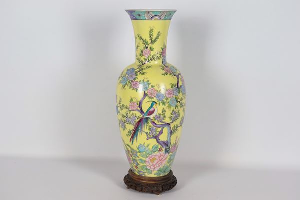 Chinese yellow porcelain trumpet vase, decorated in polychrome enamels in relief with exotic flower and bird motifs. The teak base is glued to the bottom