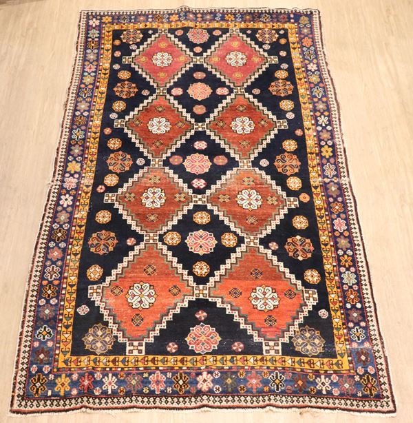 Persian Shiraz carpet with geometric designs on a blue background, various defects