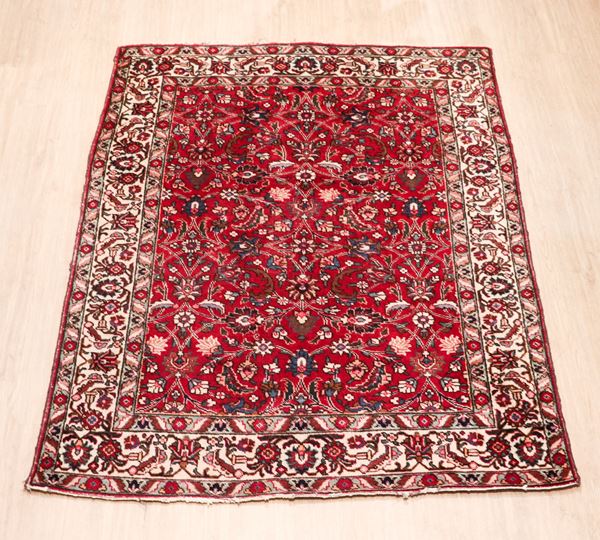 Persian Tabriz carpet with geometric and floral designs on a red background with a Havana border